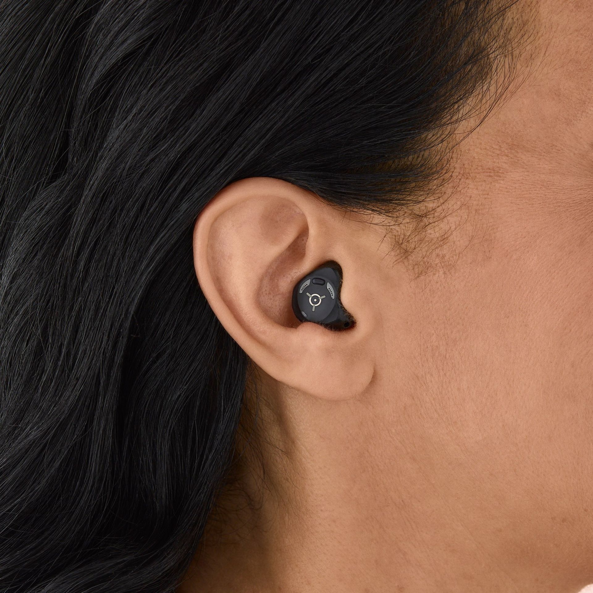 Close-up of an Ear Wearing a Small Black Wireless Earbud — Local Hearing Aid Specialists in Wallsend, NSW
