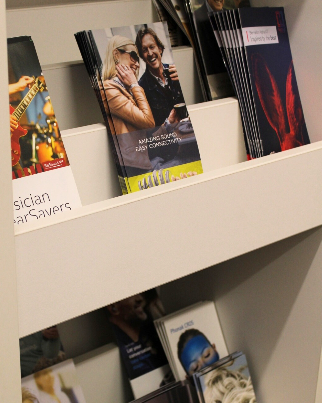 Brochures and magazines displayed on white shelves in a store or lobby — Local Hearing Aid Specialists in Wallsend, NSW