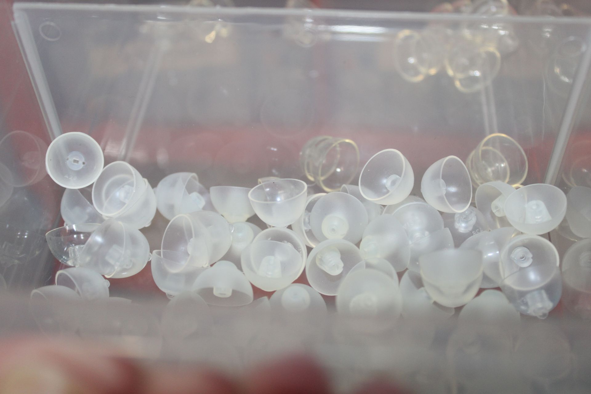 Clear plastic bin holding small translucent white and clear spherical beads — Local Hearing Aid Specialists in Wallsend, NSW