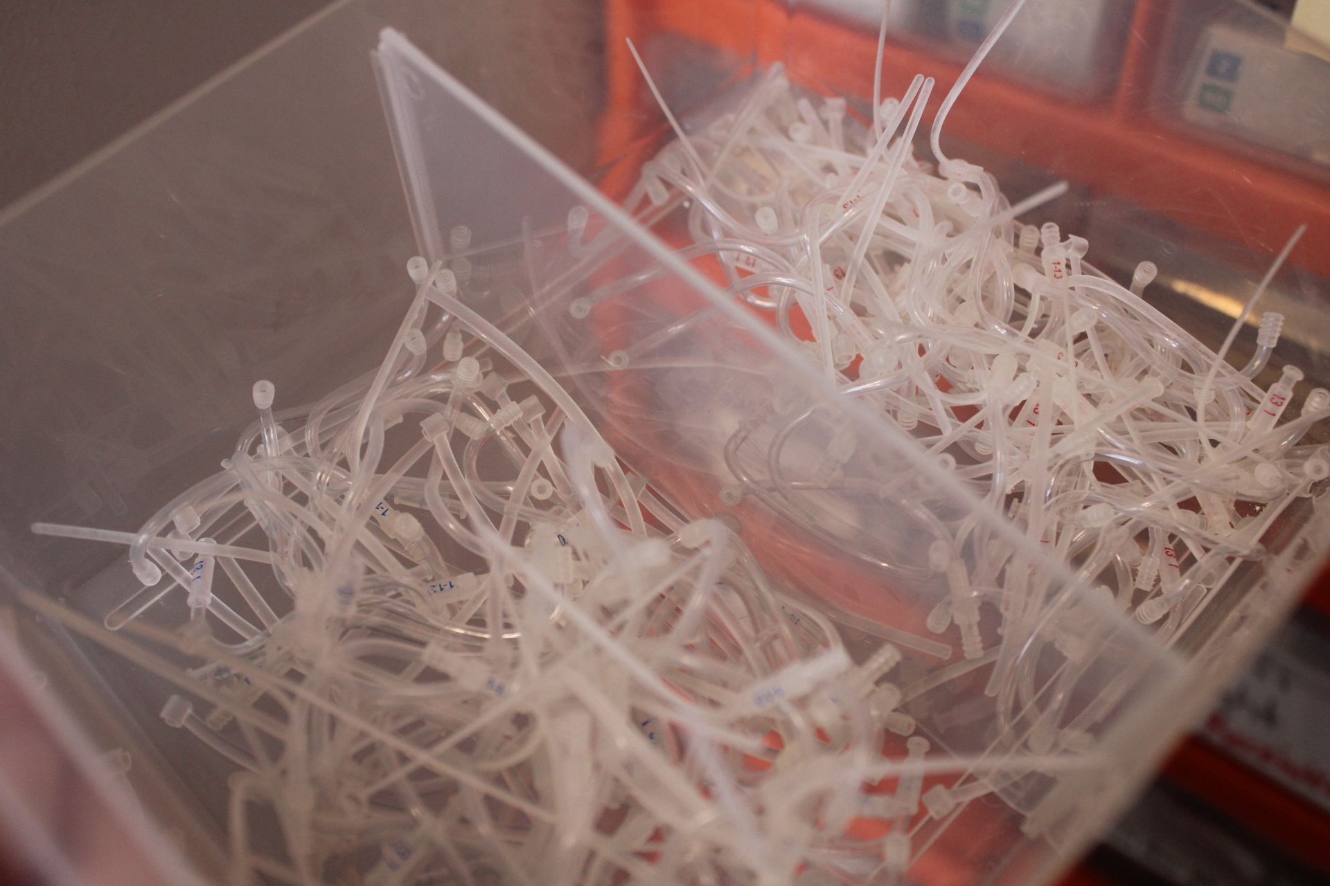 Two clear plastic bins filled with white plastic tags or clips on a red surface — Local Hearing Aid Specialists in Wallsend, NSW