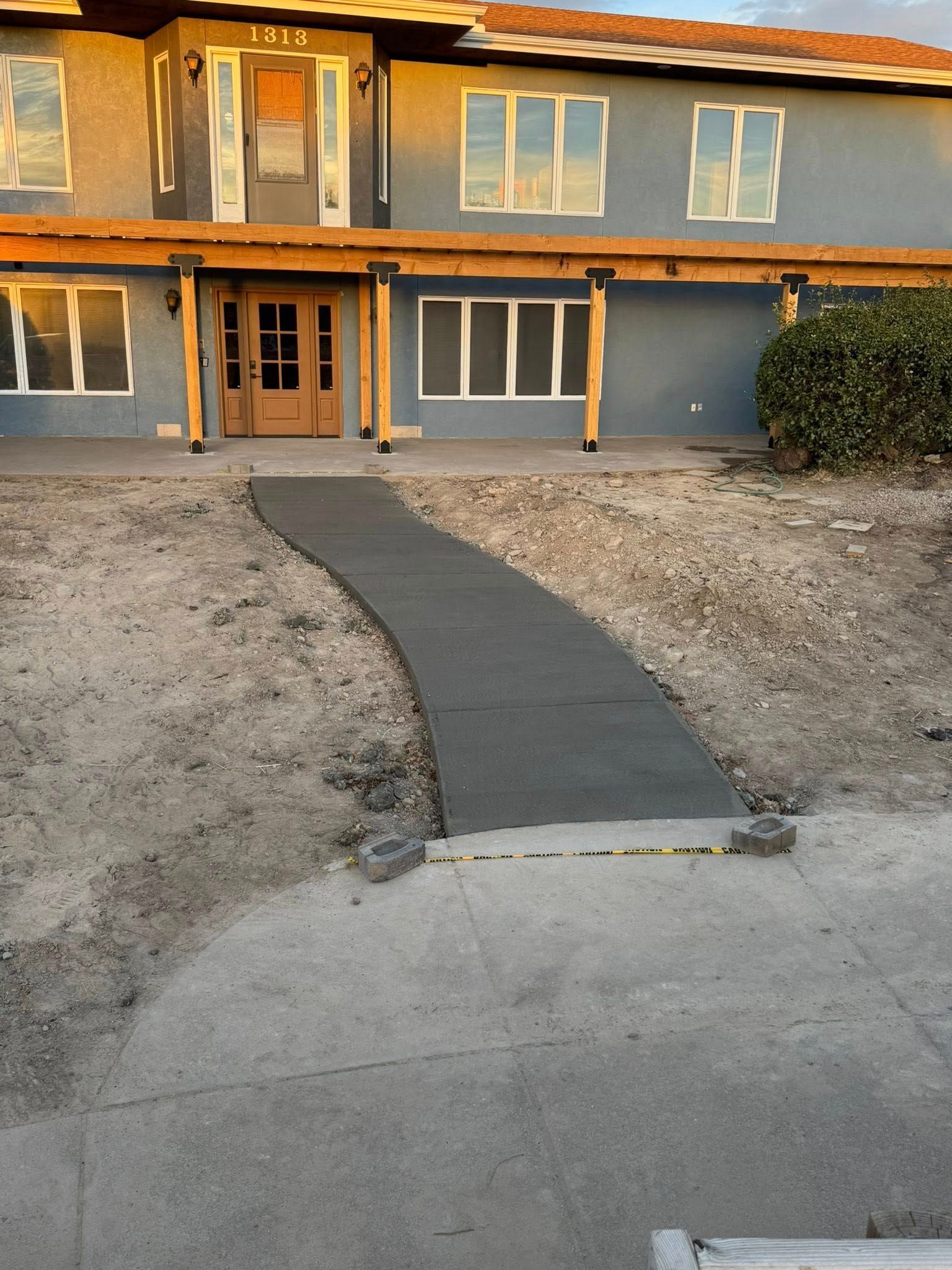 Front walkway to a gray house with a dark path leading from the driveway to the front door