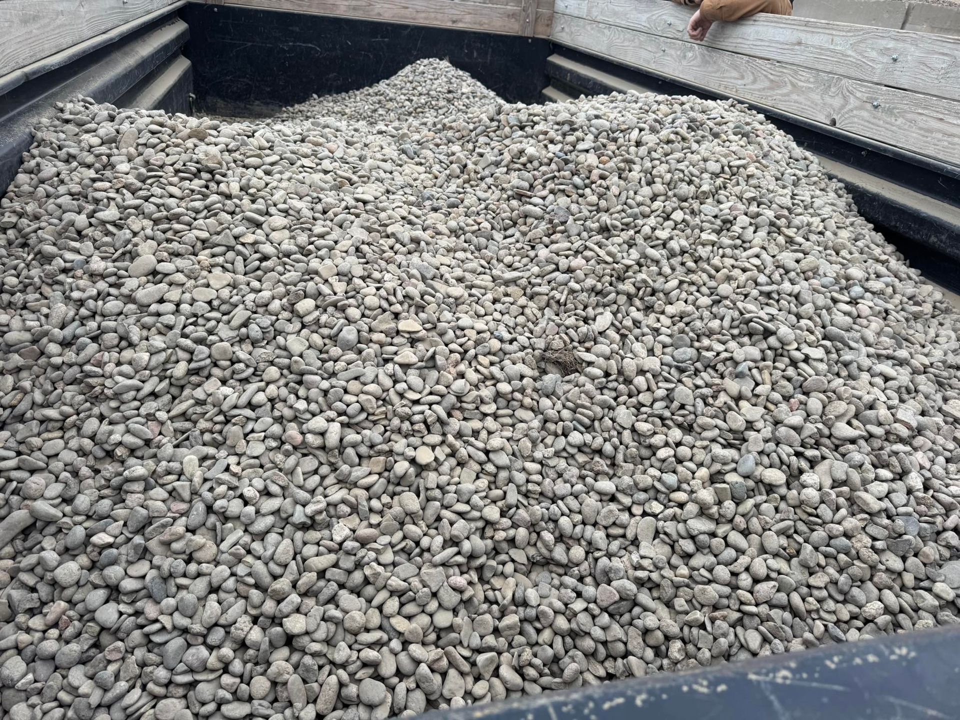 Large pile of gray gravel in a black dump truck bed