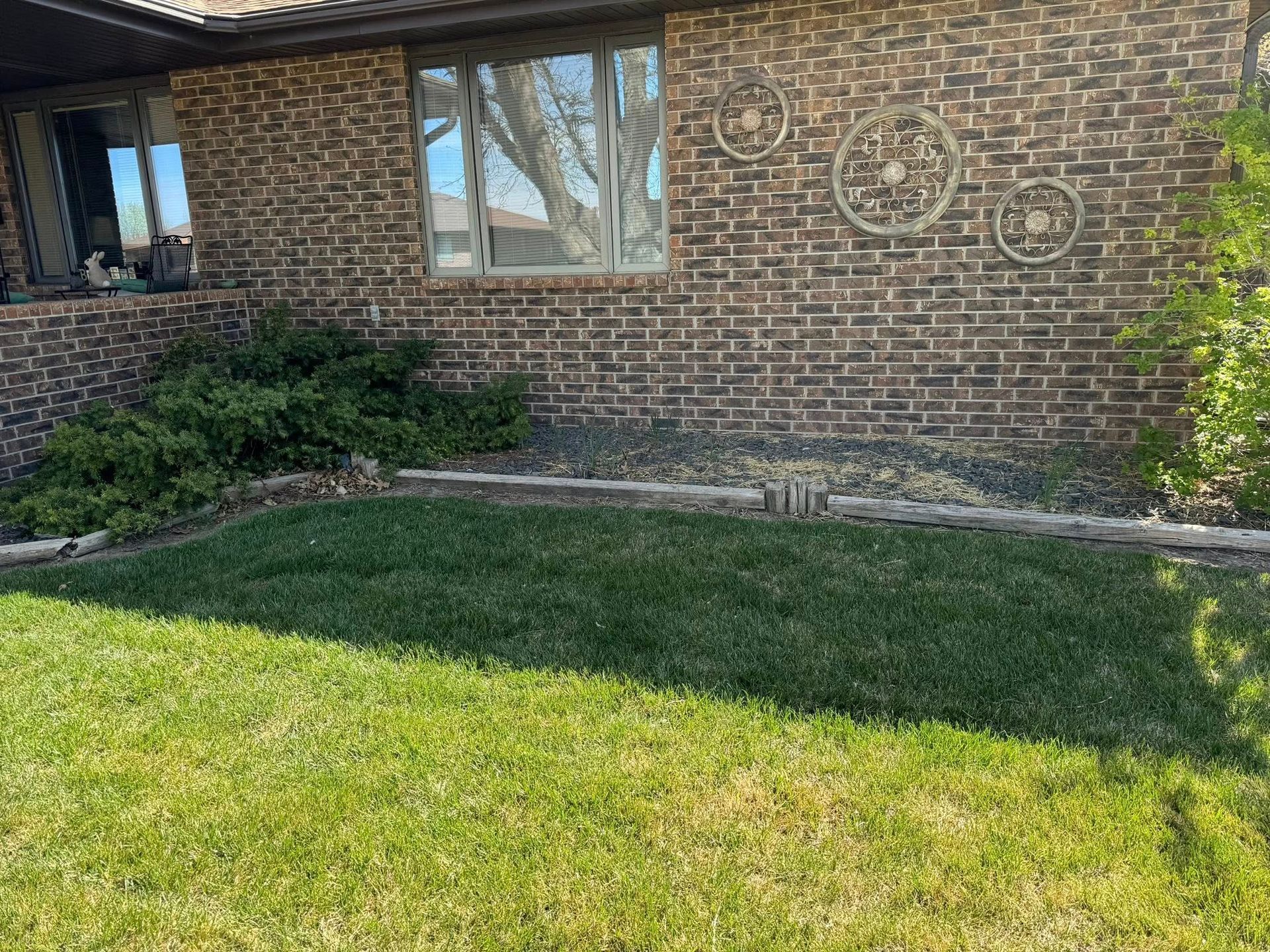 Brick house exterior with windows, circular wall decorations, and a green front lawn.