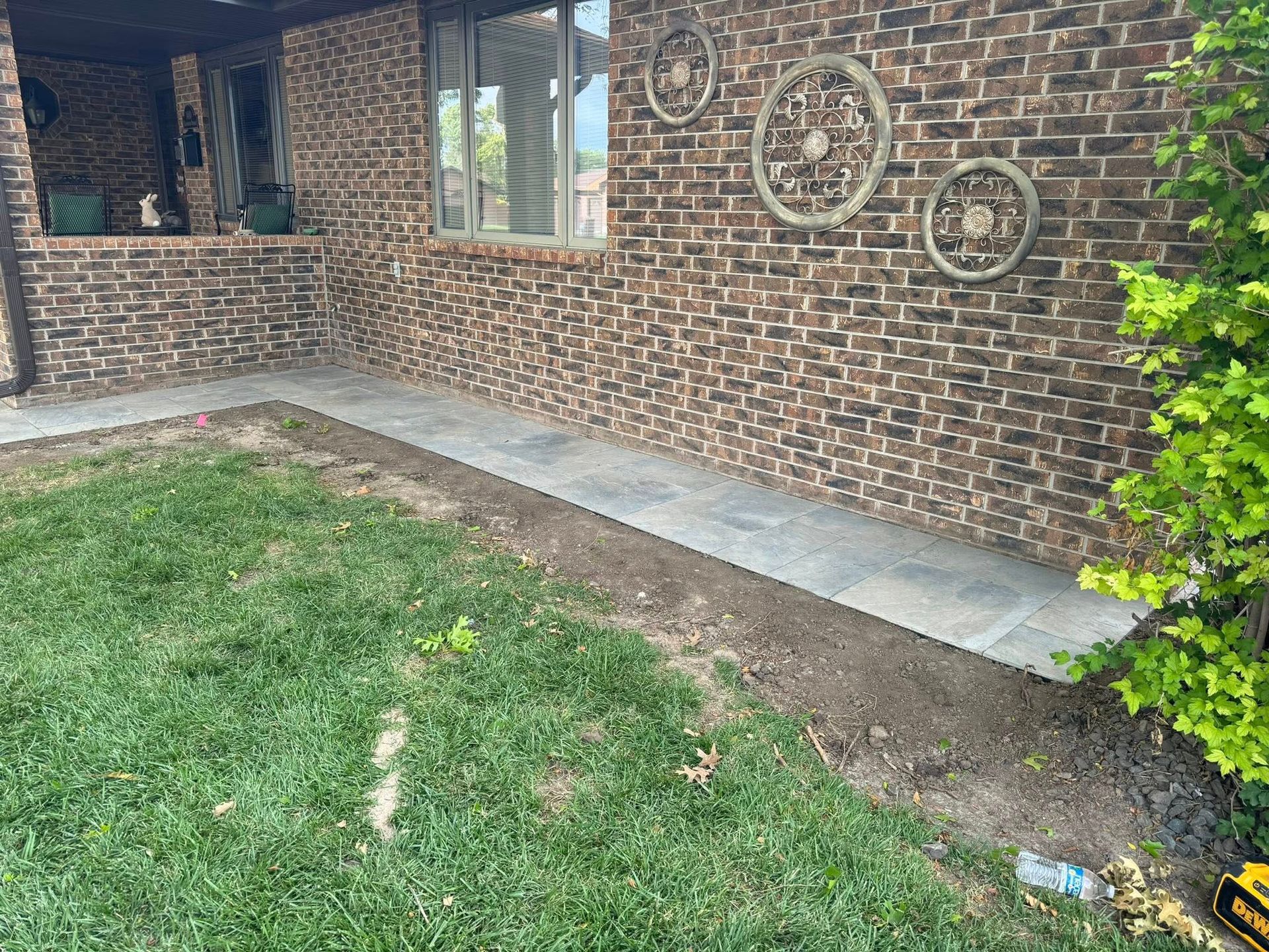 Brick house porch with concrete patio, grassy yard, and decorative wall circles