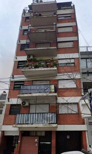 Edificio de apartamentos alto de ladrillo rojo con balcones, ventanas y un garaje en la planta baja 