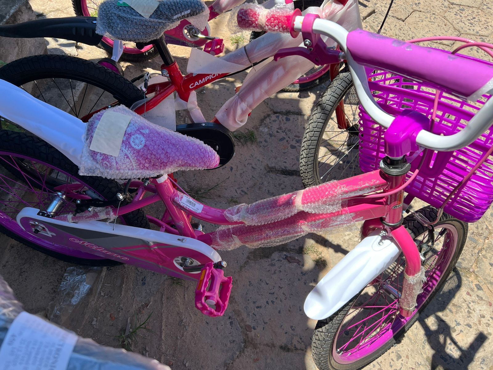Varias bicicletas infantiles de color rosa y morado estaban aparcadas al aire libre sobre grava.