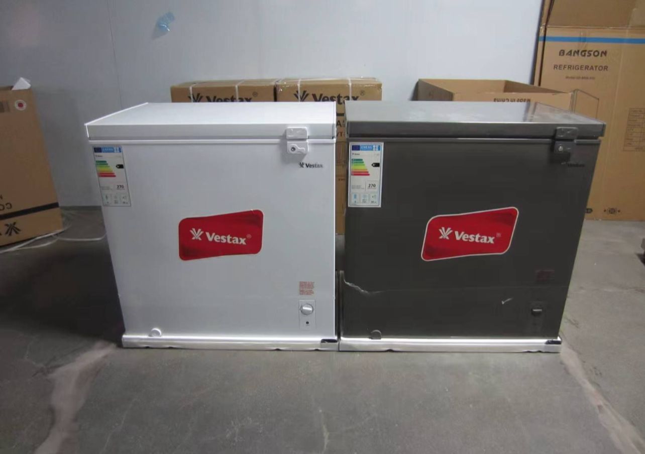 Congelador horizontal Vestax negro en un pasillo de la tienda con suelo de baldosas, con etiqueta energética y tapa superior.