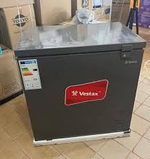 Congelador horizontal Vestax negro en un pasillo de la tienda con suelo de baldosas, con etiqueta energética y tapa superior.