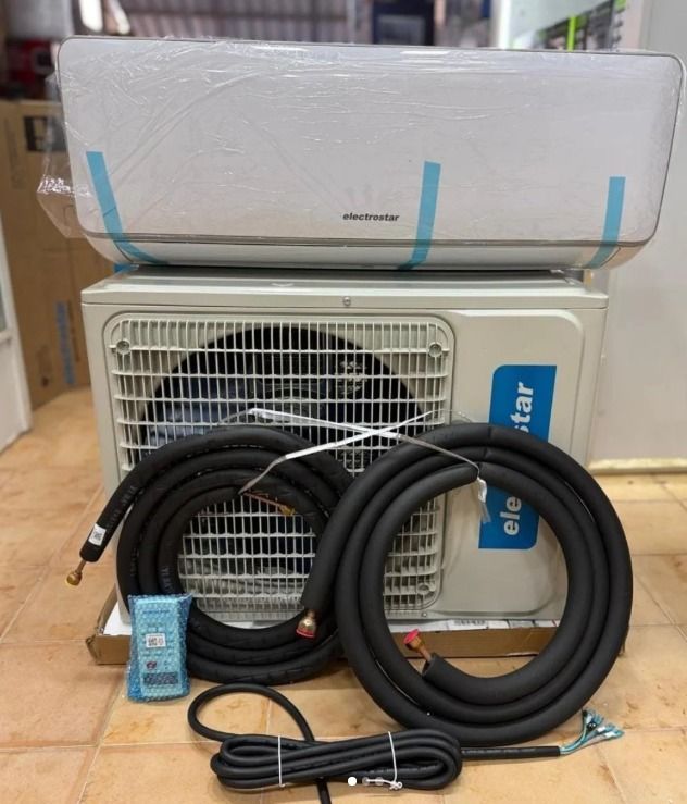 Dos cajas de cartón de Elecrostarr apiladas en un terreno de hormigón soleado cerca de camiones rojos y azules.