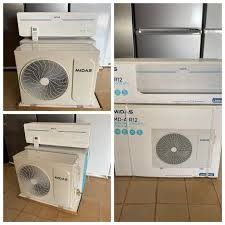 Unidad exterior de aire acondicionado MIDAS blanca con ventilador grande, envuelta en plástico y colocada sobre un palé.