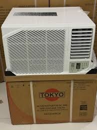 Un aire acondicionado de ventana blanco está sobre una caja de cartón con la etiqueta 
