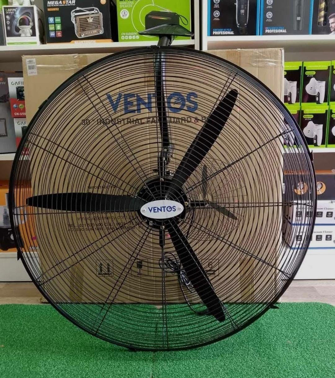 Ventilador de pared industrial negro con cuatro aspas y rejilla metálica sobre una base.