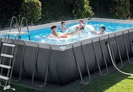 Personas relajándose en una piscina elevada con escalera y manguera de filtro en un patio trasero.