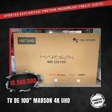 Una gran caja de cartón para televisor con la etiqueta “Mazon” y “Powered by webOS Hub” sobre un suelo de baldosas.