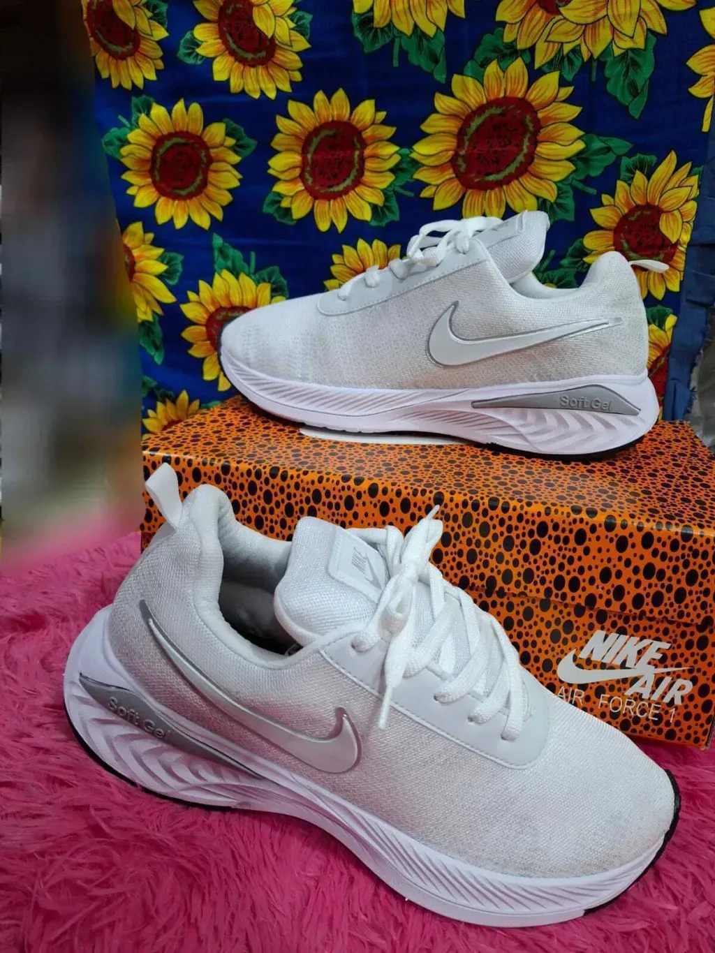Zapatillas de running Nike negras sobre una caja con estampado de leopardo y un fondo de girasoles.