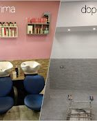 Interno di un salone con pareti rosa e grigie, scaffali per prodotti e sedie blu e beige vicino alla zona lavabo.