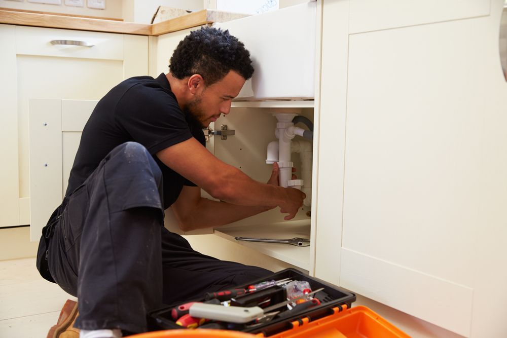 Plumber Working Under a Kitchen Sink — Zac Rennick Plumbing in Yeoval, NSW
