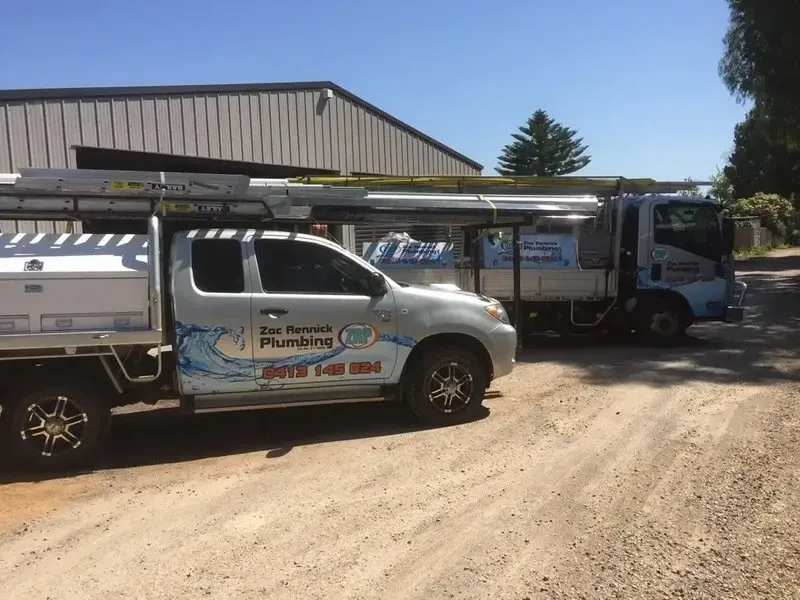 Two Plumbing Trucks Parked on a Gravel Drive — Zac Rennick Plumbing in Dubbo, NSW