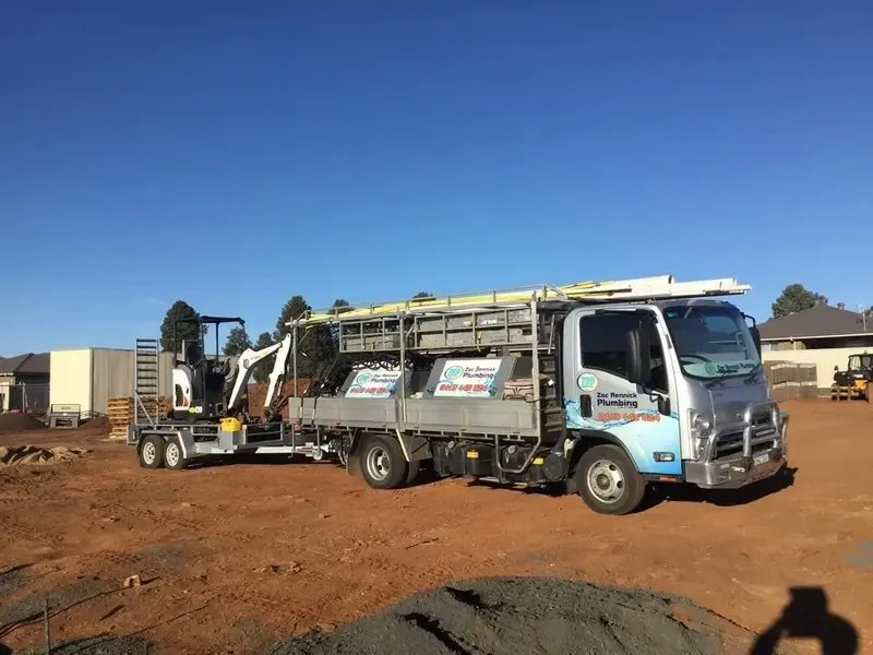 Truck With Attached Trailer Carrying a Small Excavator — Zac Rennick Plumbing in Dubbo, NSW
