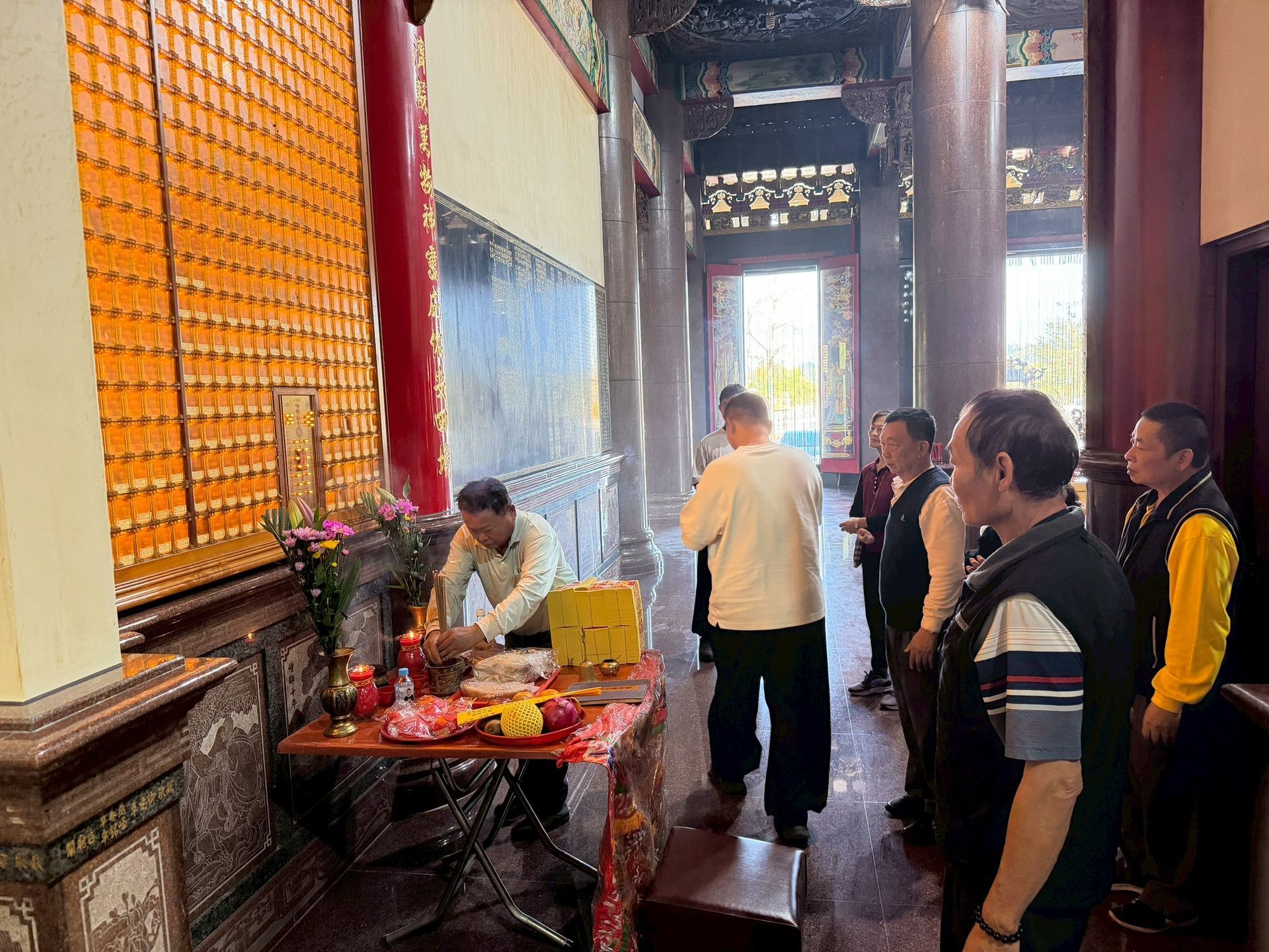 寺廟祭壇前的人們，擺放著祭品，還有人在照顧他們。