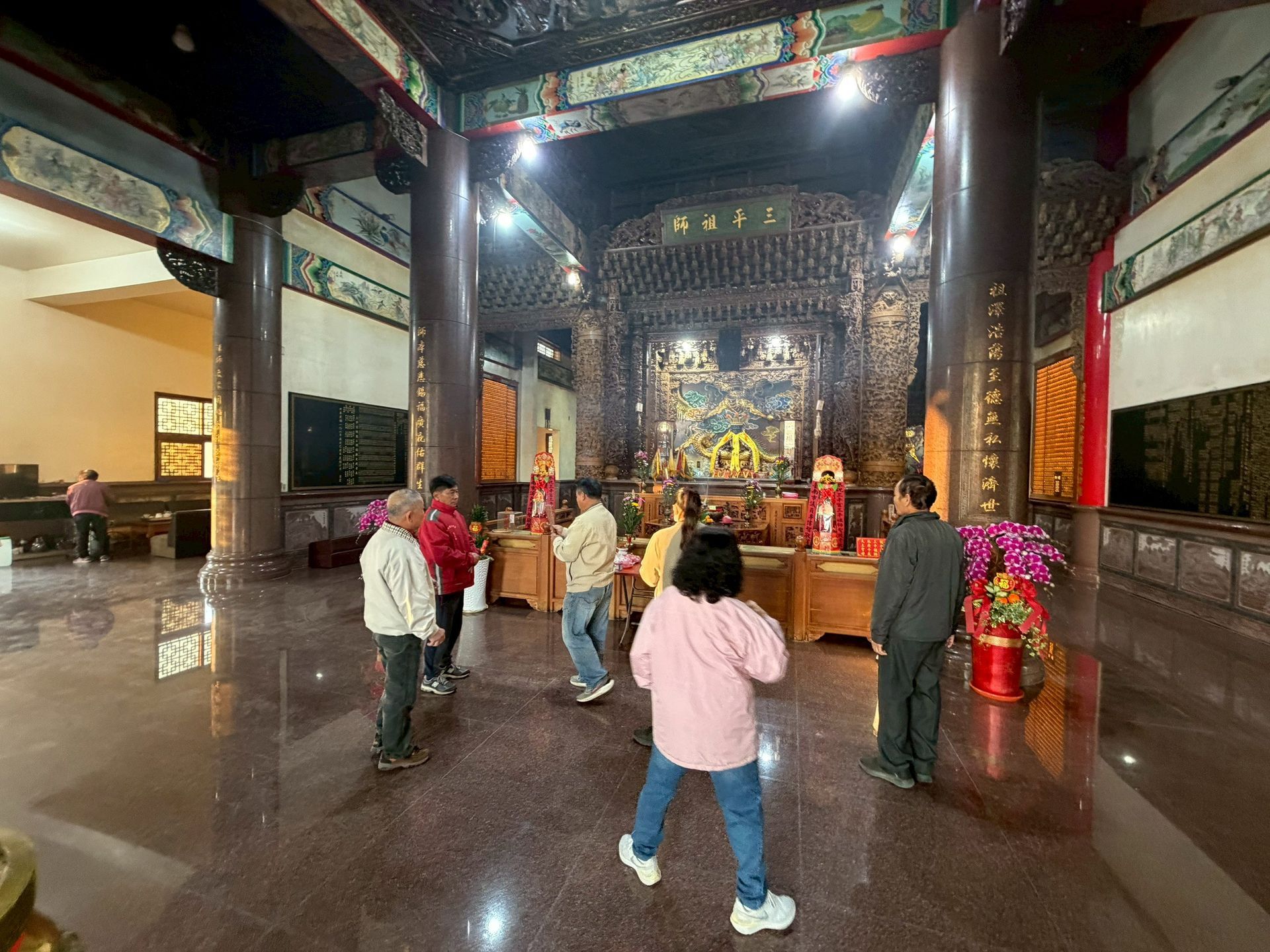 寺廟大殿內的人們；精美的雕刻、柱子和宗教人物。