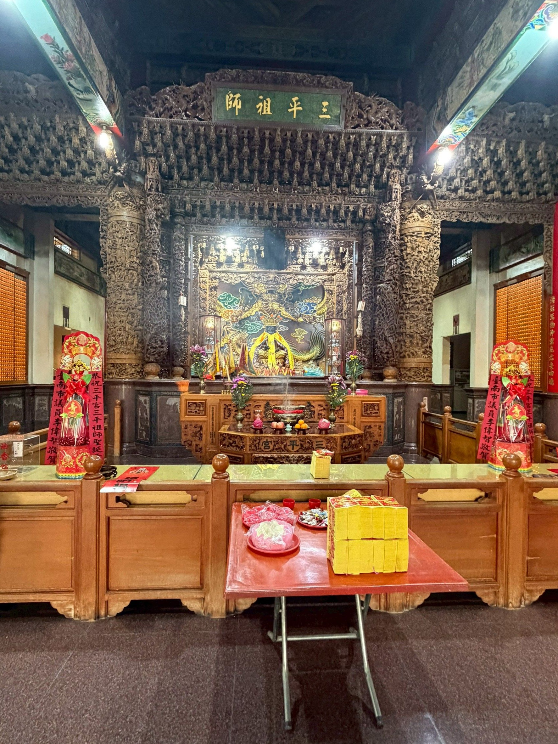 傳統寺廟內部，裝飾華麗的木雕、祭壇和供品。
