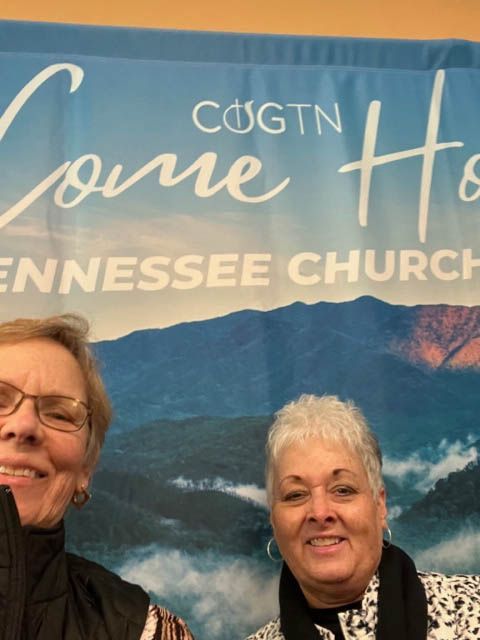 Two women standing in front of a banner that says come home tennessee church