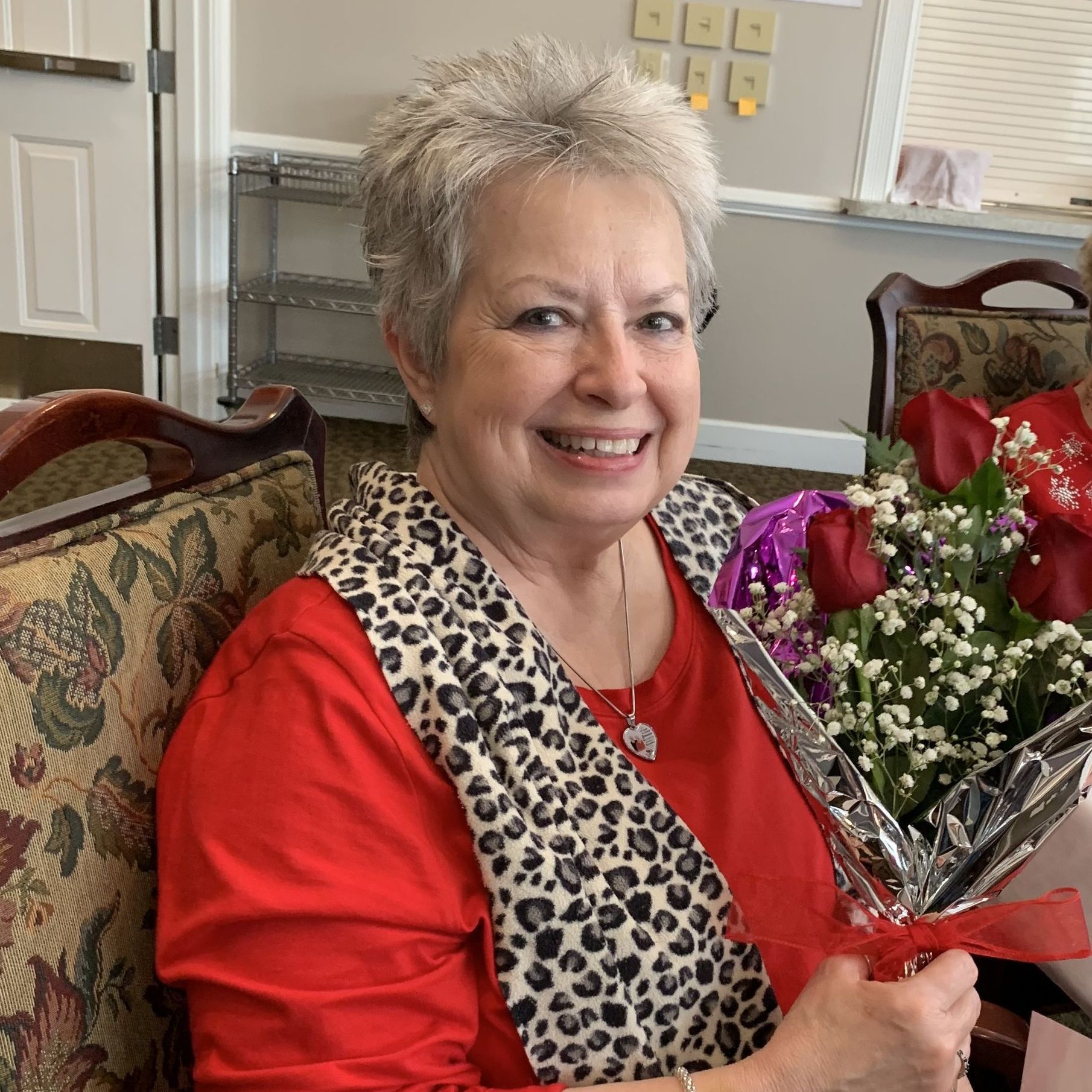 A woman is sitting in a chair holding a bouquet of flowers.