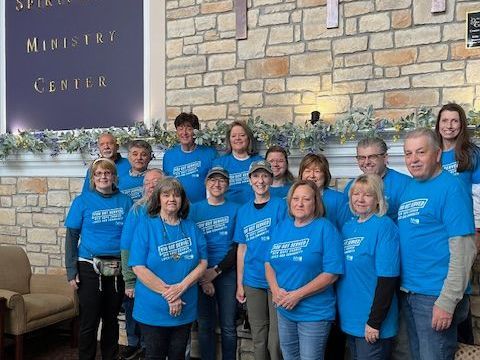 A group of people wearing blue shirts are posing for a picture.