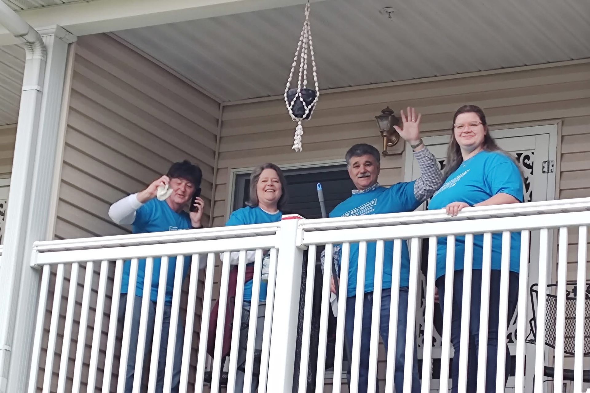 A group of people standing on a porch wearing blue shirts