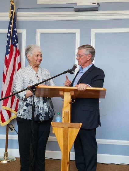 A man and a woman standing at a podium with an american flag in the background