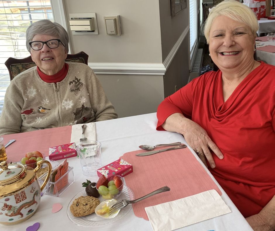 Two women are sitting at a table with food on it