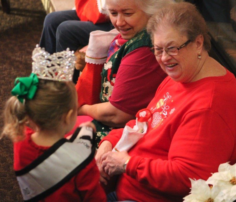 A woman in a red shirt is talking to a little girl