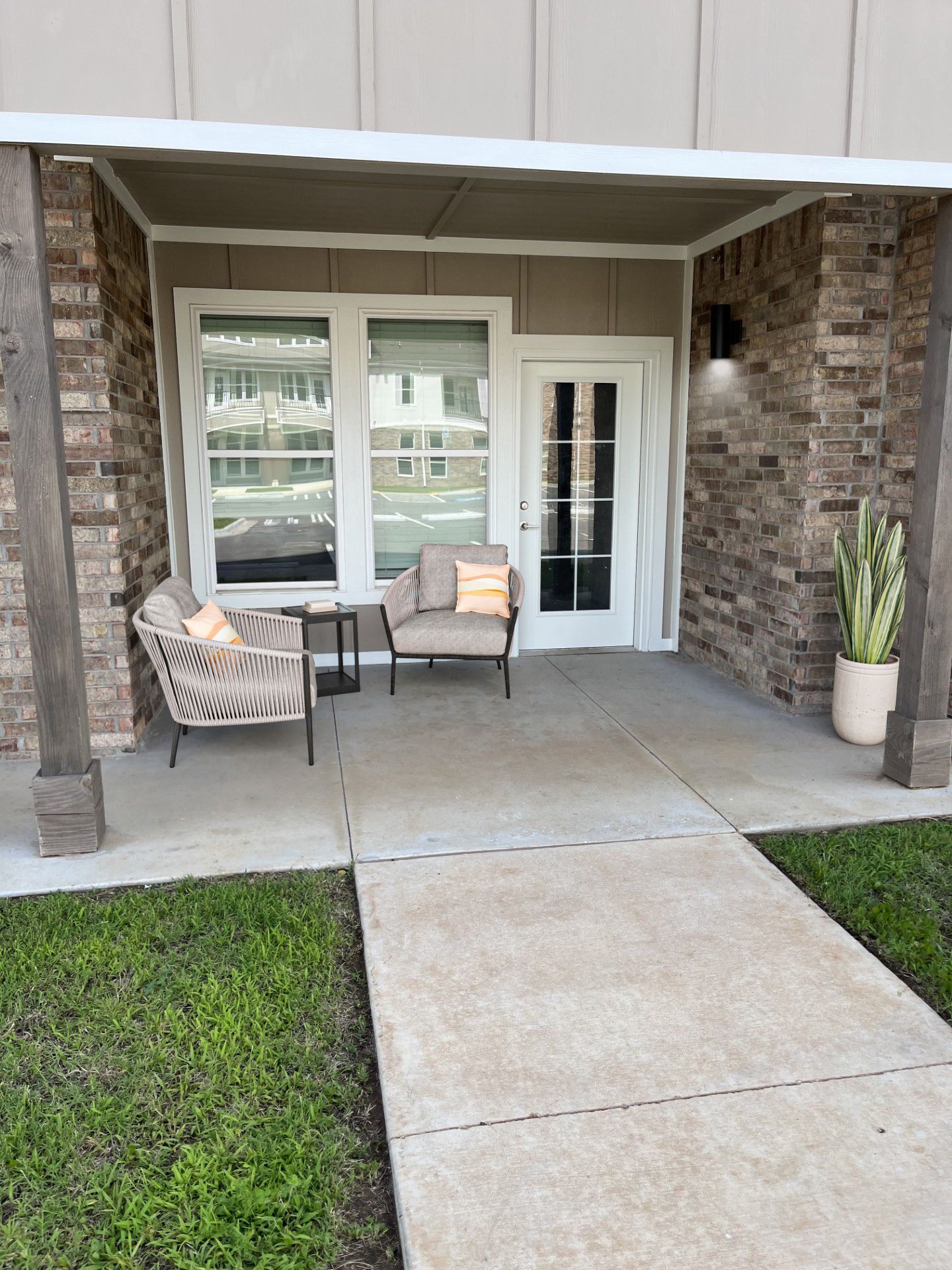 A patio with chairs and a table in front of a house.