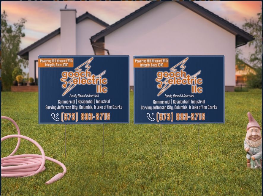 Two identical yard signs for Gooch Electric LLC, featuring a lightning bolt logo, displayed on a residential lawn.