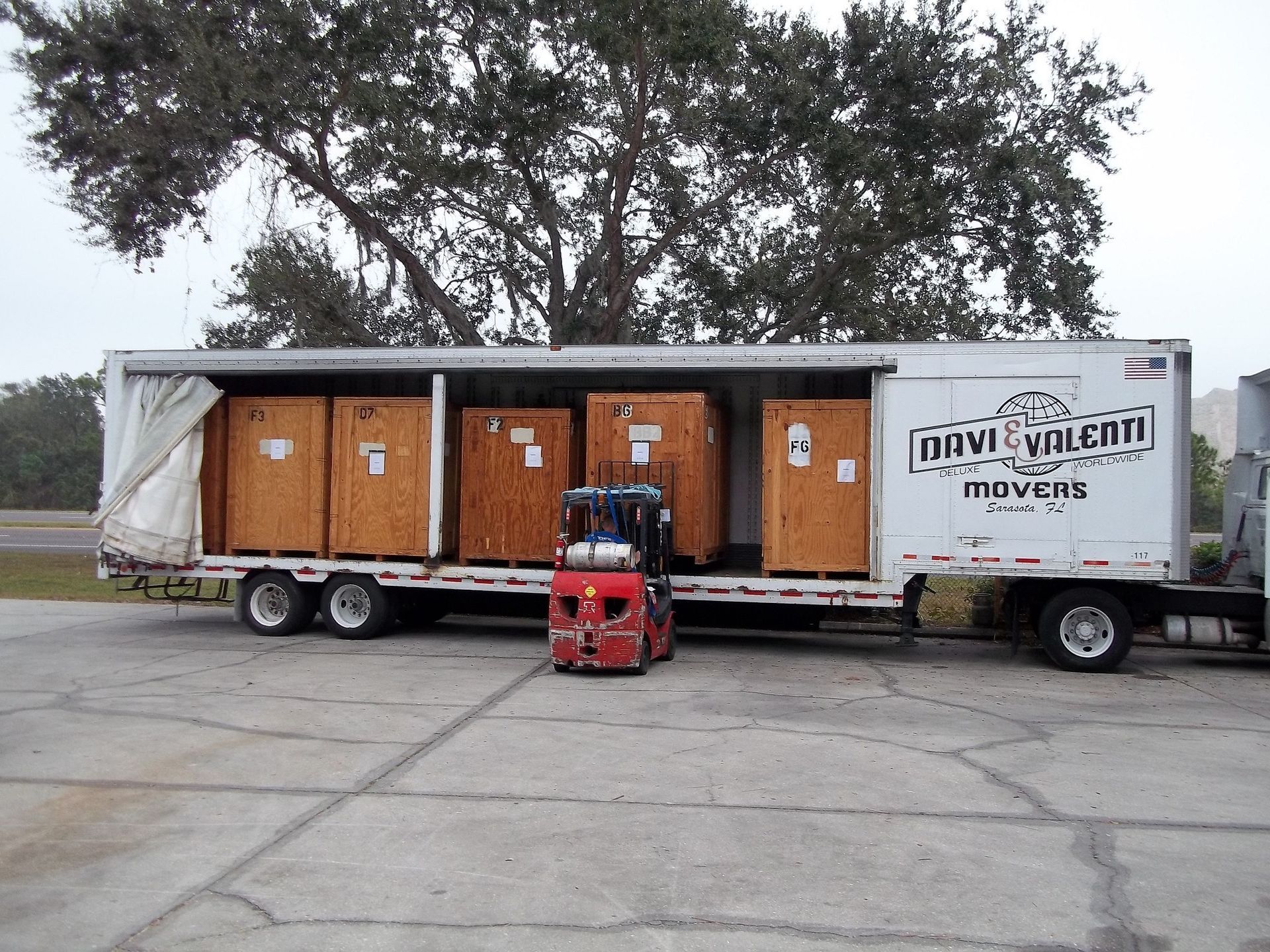 Forklift loading wooden crates into a white trailer labeled 