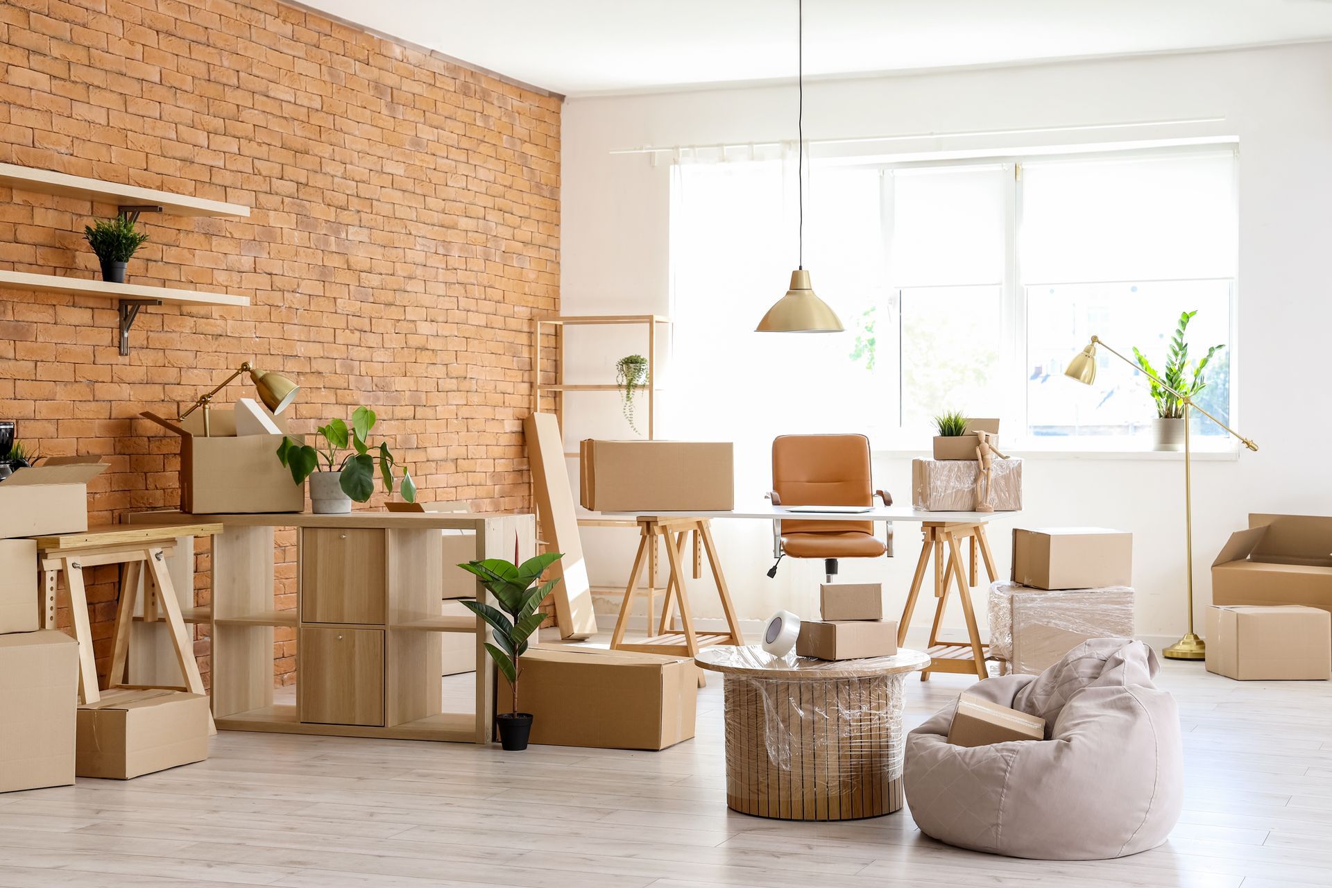 Bright minimalist studio with brick wall, wooden desks, plants, and a beanbag by a sunlit window