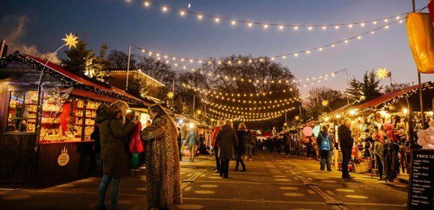 A small street lined with warm lights and Christmas vendors.