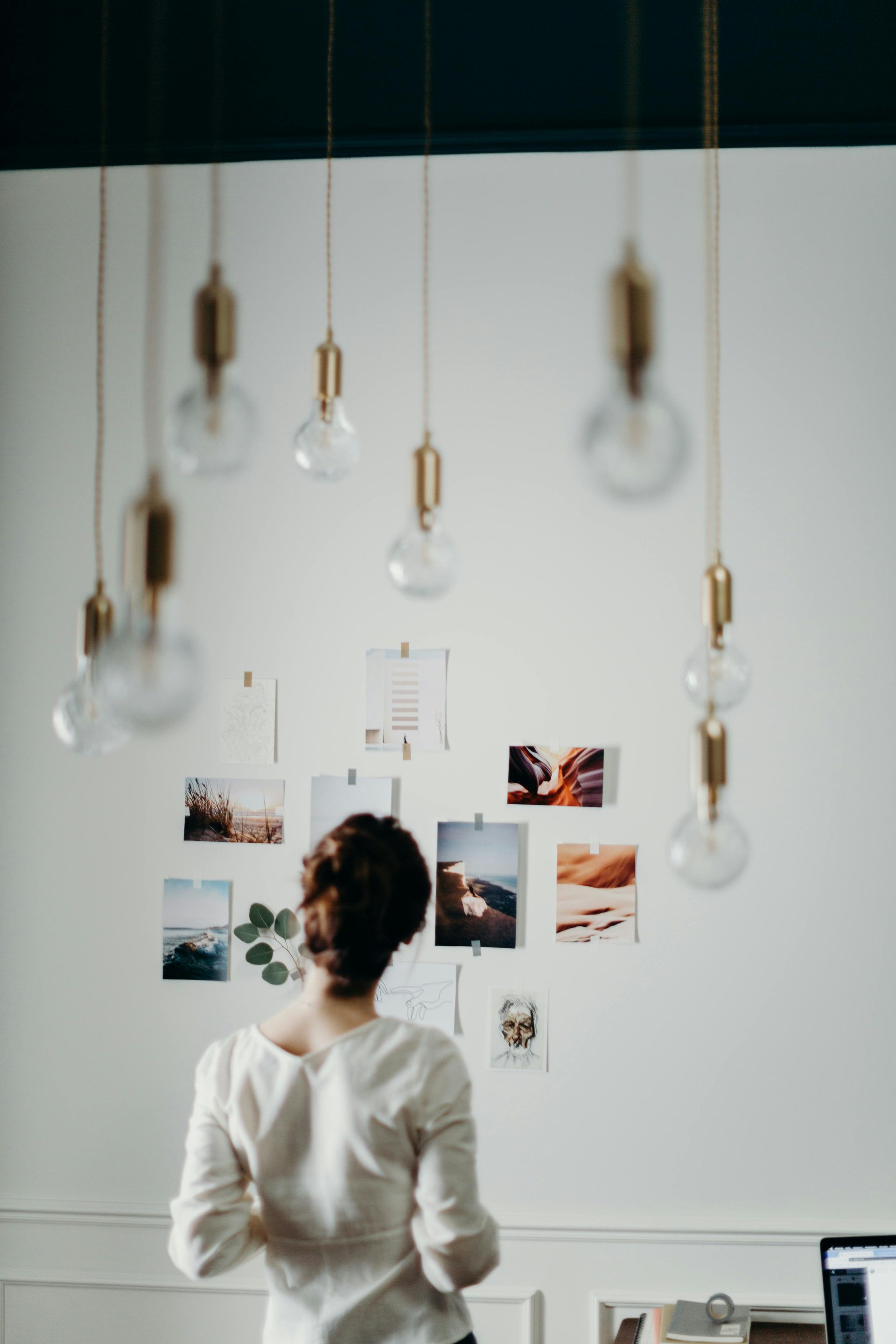 A woman is looking at a vision board on a wall in her home.