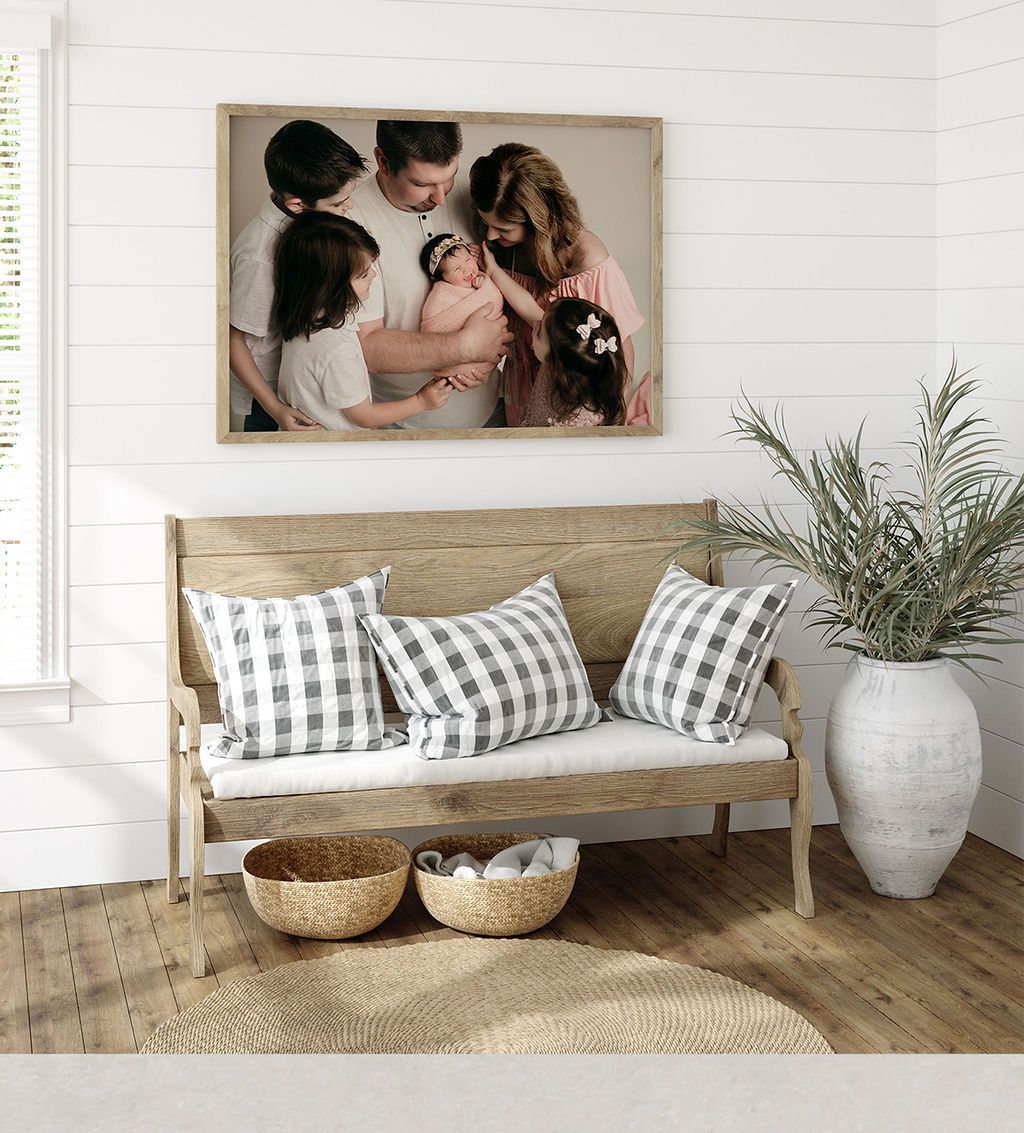 Family portrait over bench with pillows, baskets, and potted greenery.