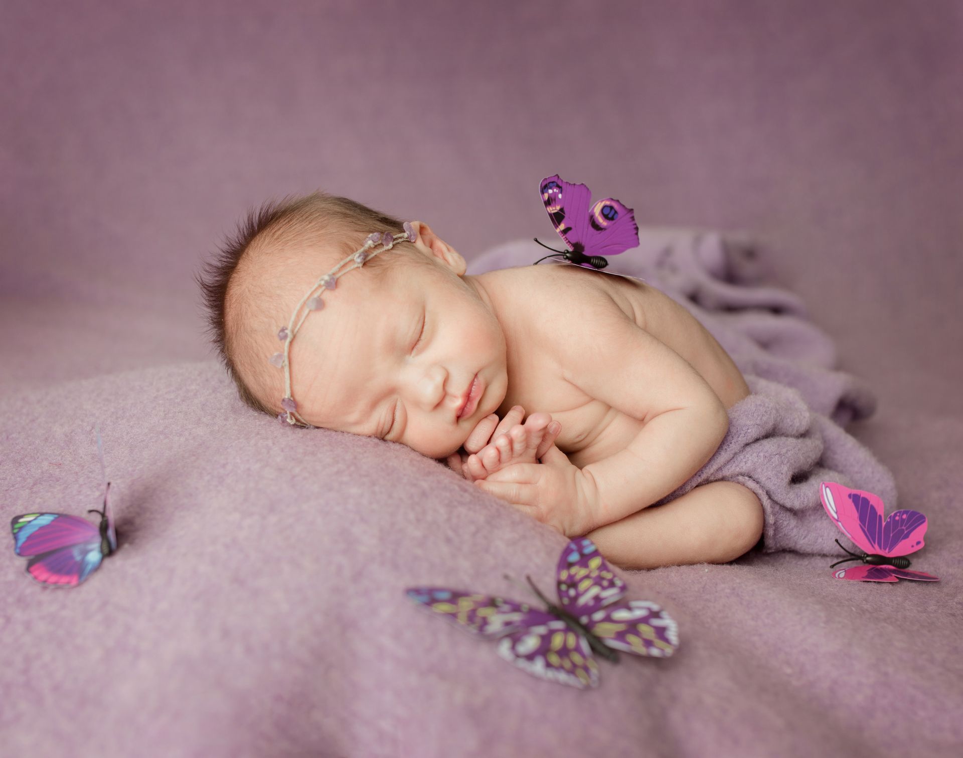 Sleeping baby on lavender blanket, adorned with butterfly decorations.