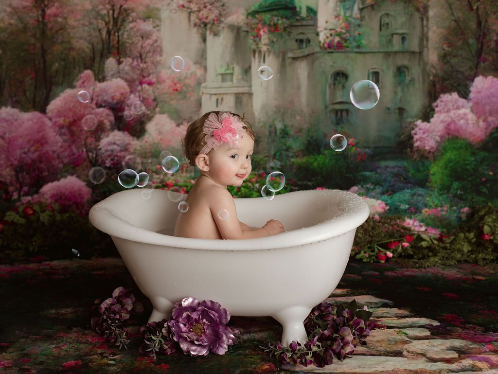 Baby in clawfoot tub with bubbles, pink flower crown, fairytale backdrop.