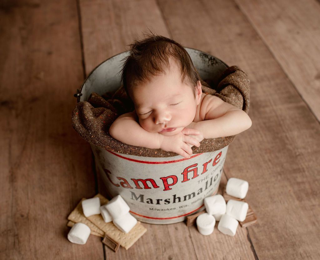 Newborn baby sleeping in a bucket labeled