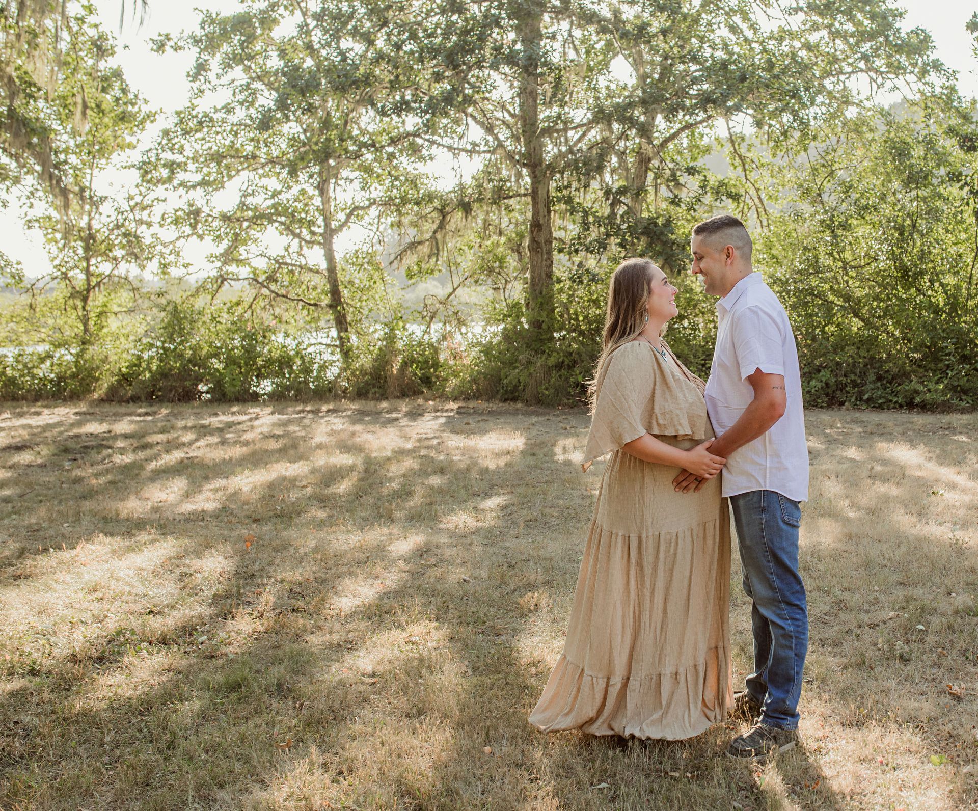 Couple holding hands, looking at each other in a sunny outdoor setting; 
