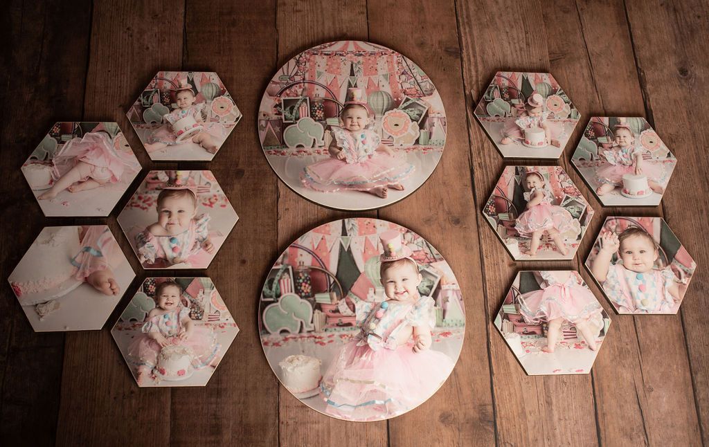 Baby photos printed on round and hexagonal tiles, displayed on wood surface.