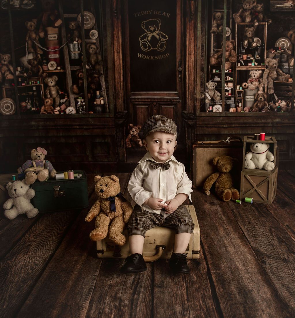 Boy in cap, bow tie, and knickers sits with teddy bears in a vintage toy shop setting.