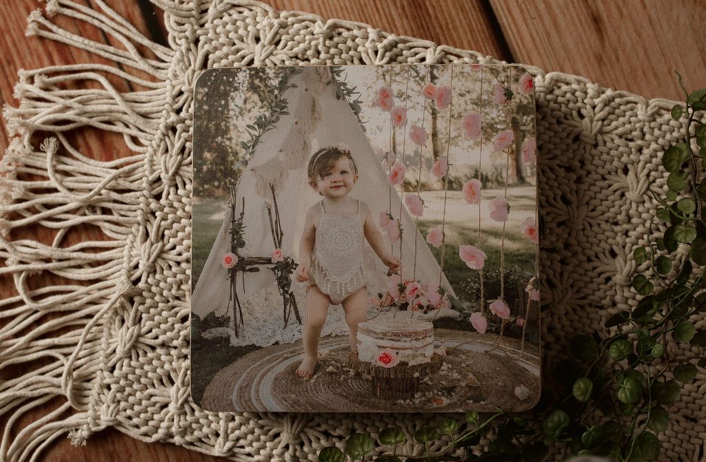 Child standing in front of a teepee, surrounded by flowers.