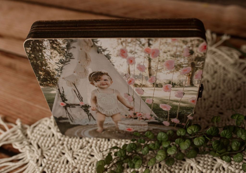 Box with photo of a child in a teepee, surrounded by pink flowers.