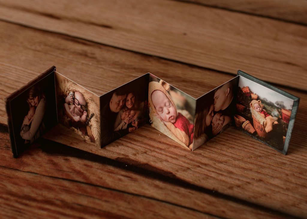 Accordion-style photo booklet with multiple images of a baby, displayed on a wooden surface.