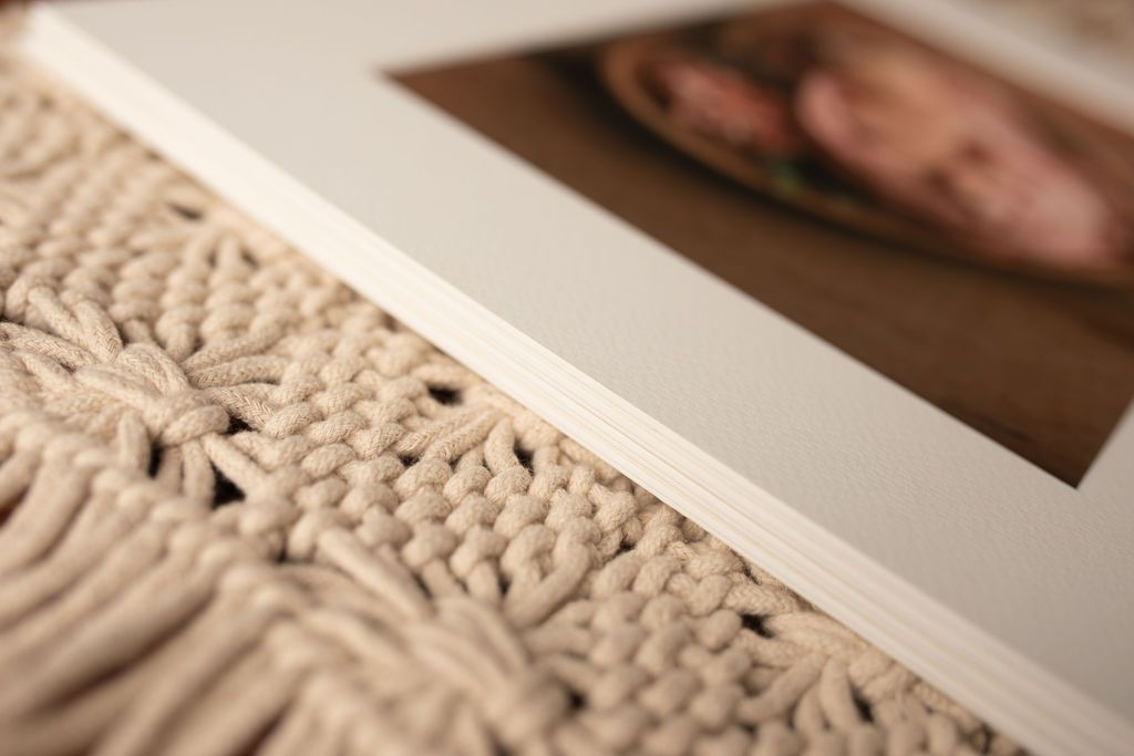Close-up of a white matted photo frame on a textured, off-white surface, with a blurred photo visible.
